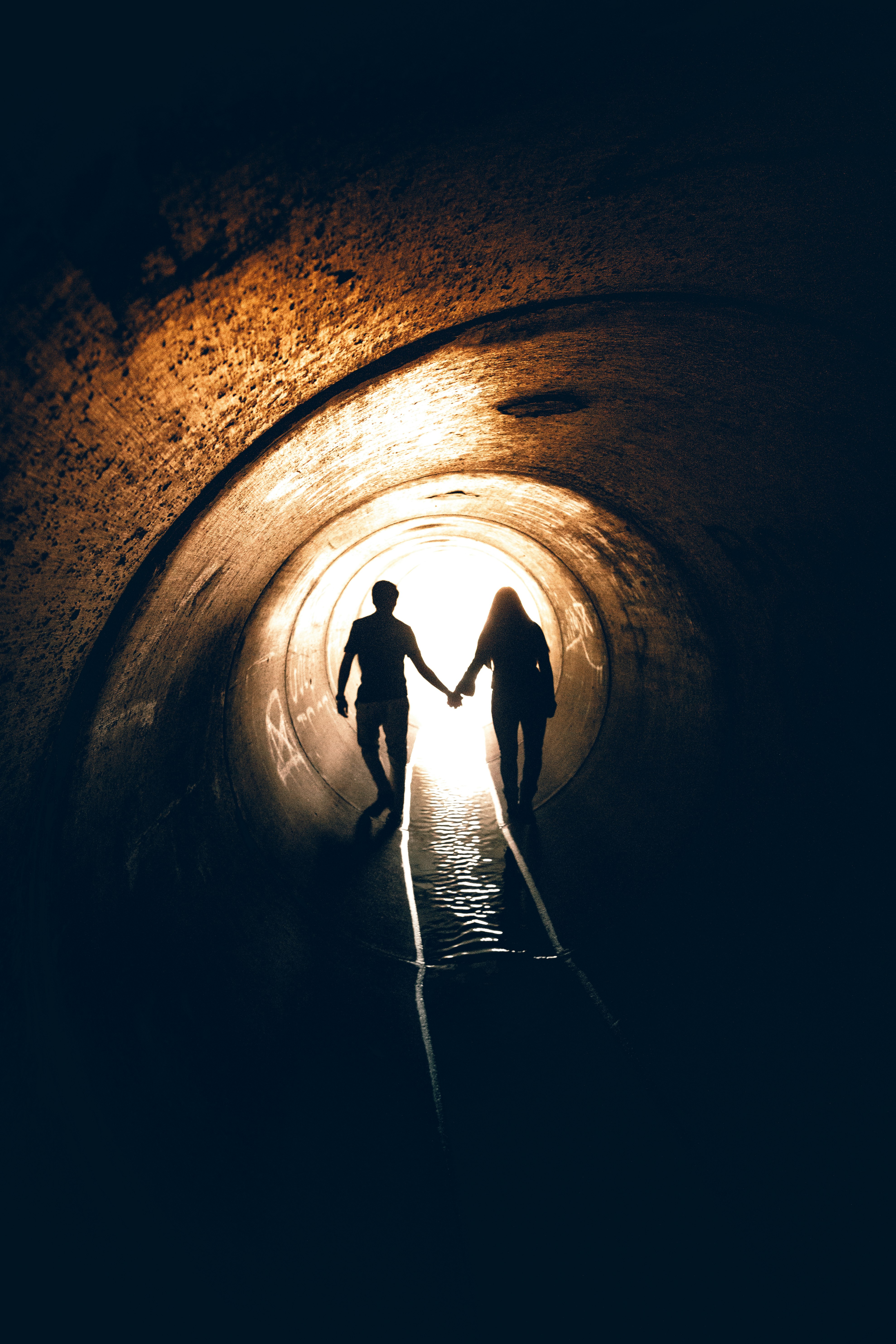 silhouette of man and woman inside tunnel